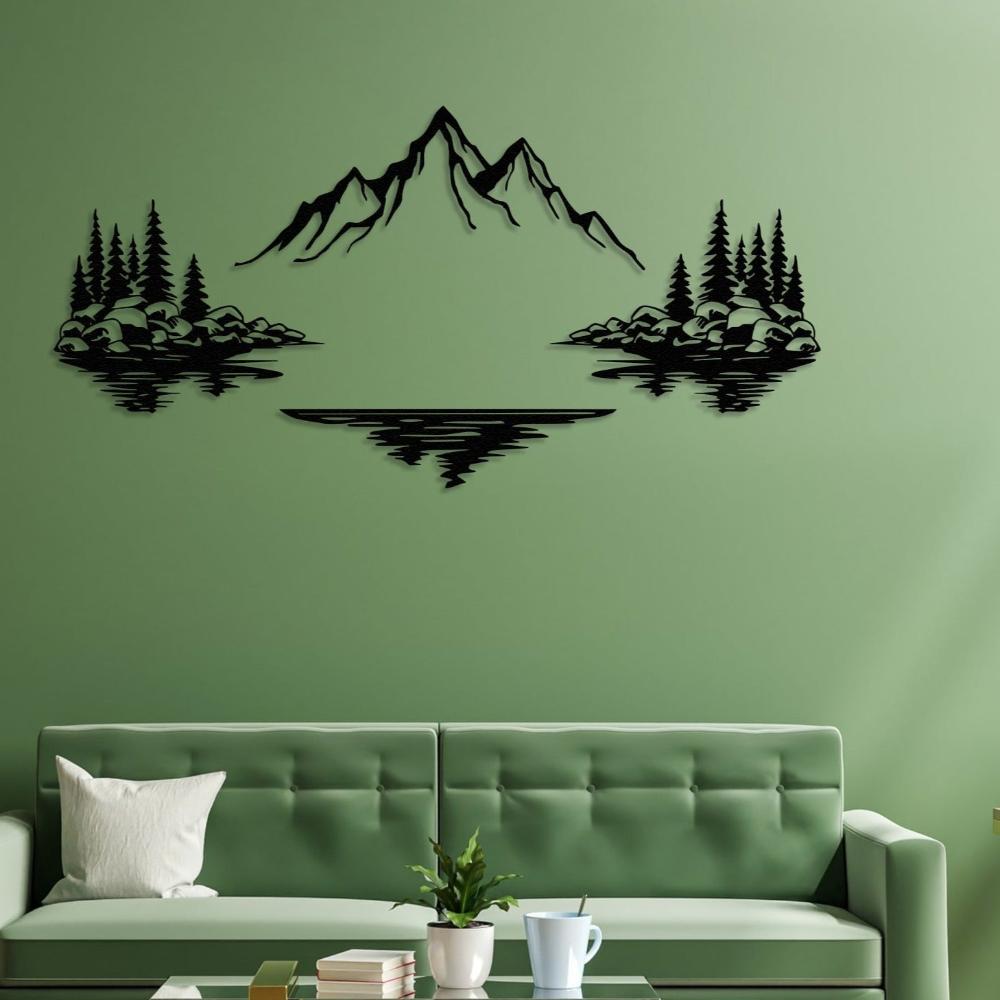 Nature-themed metal wall art depicting a mountain in the center with trees and rocks on either side, reflecting in a lake below, mounted on a green wall above a modern green sofa.