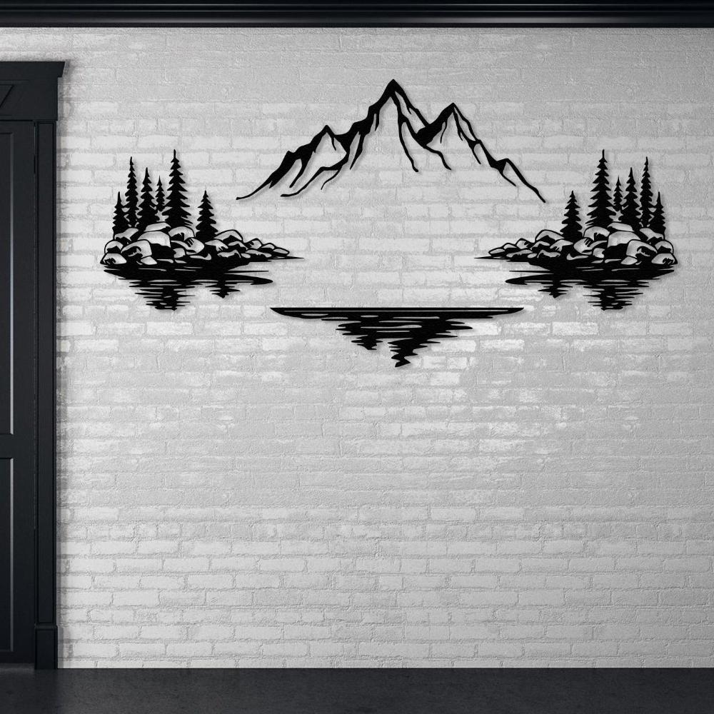 Nature-themed metal wall art showcasing a mountain with snow caps in the center, bordered by trees and rocks on both sides, with their reflections in a lake below, mounted on a white brick wall.