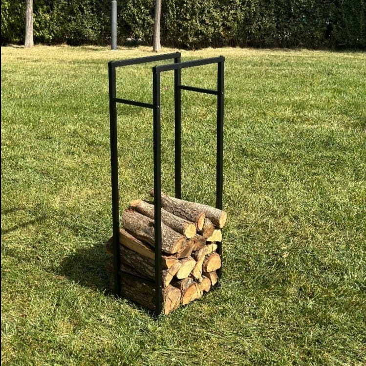 A sturdy black metal firewood rack filled with neatly stacked logs, placed on a vibrant green lawn outdoors. The natural setting emphasizes the rack's durability and functionality for outdoor use.