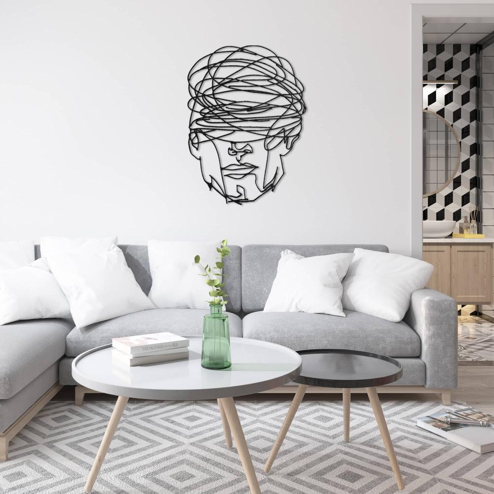 Contemporary living room featuring "Overthinking Man" black metal wall art mounted on a white wall above a gray sectional sofa with white pillows, complemented by a geometric patterned rug, a minimalist coffee table, and an open view into a stylish bathroom.