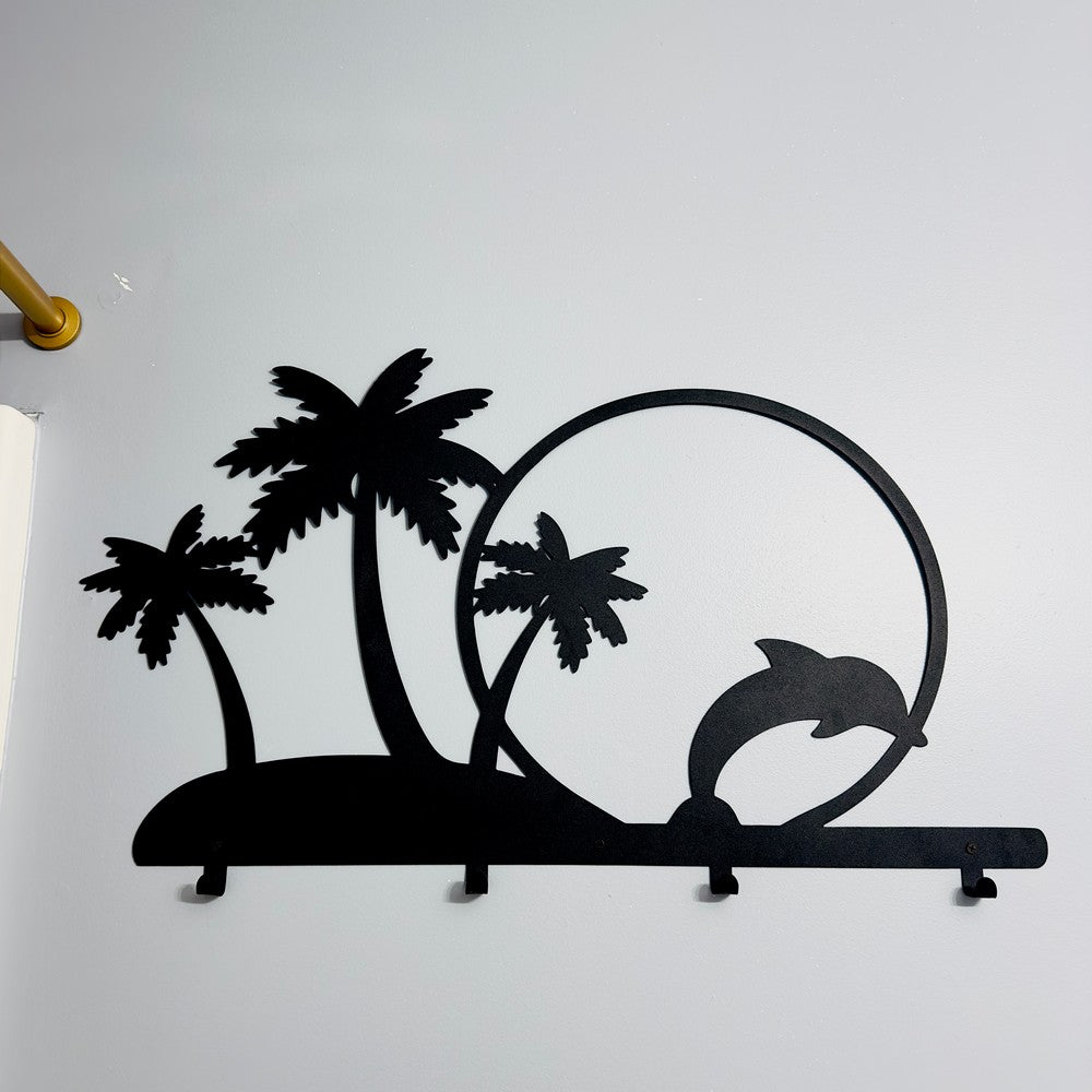 A black metal wall-mounted rack featuring palm trees and a dolphin jumping through a circle. The tropical-themed design includes hooks for hanging items, offering a functional and decorative element for wall decor.