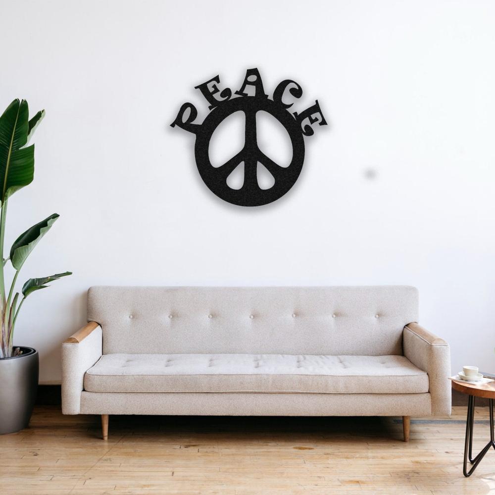 A modern living room featuring a neutral beige sofa with a black "Peace" metal wall art mounted on a white wall. A potted green plant adds a touch of freshness to the space.