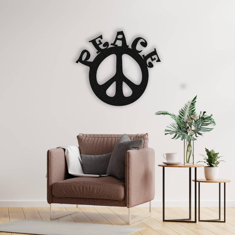 A cozy corner with a taupe armchair and side tables holding a vase with greenery, paired with a black "Peace" metal wall art on a white wall. The space exudes comfort and tranquility.