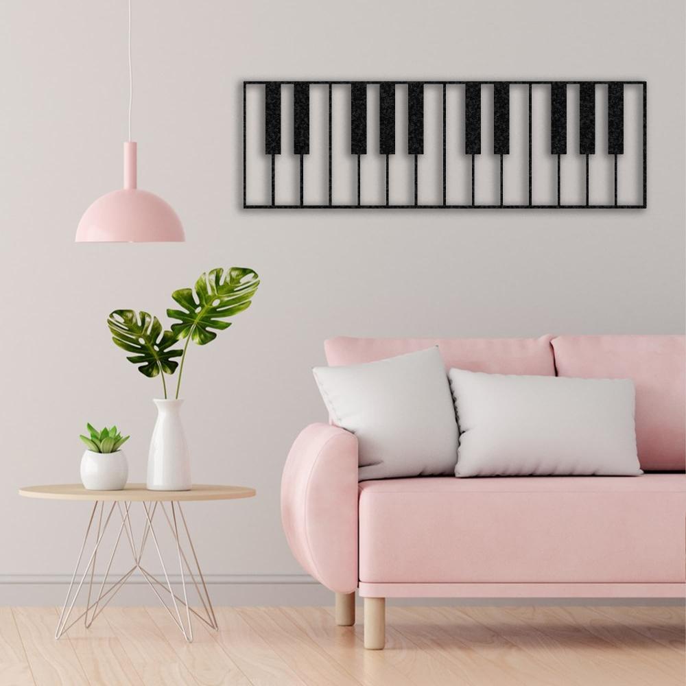 Piano keys-themed black metal wall art mounted on a light beige wall, complementing a pastel pink sofa, white cushions, a modern side table with potted plants, and a pink pendant lamp.