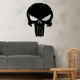 Black metal Punisher skull wall art displayed on a light beige wall above a modern gray sofa, with a natural wood and wicker side table nearby.