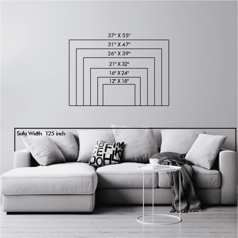 Puzzle piece metal wall art size chart with dimensions ranging from 12"x18" to 37"x55", placed above a white sofa for visual reference.