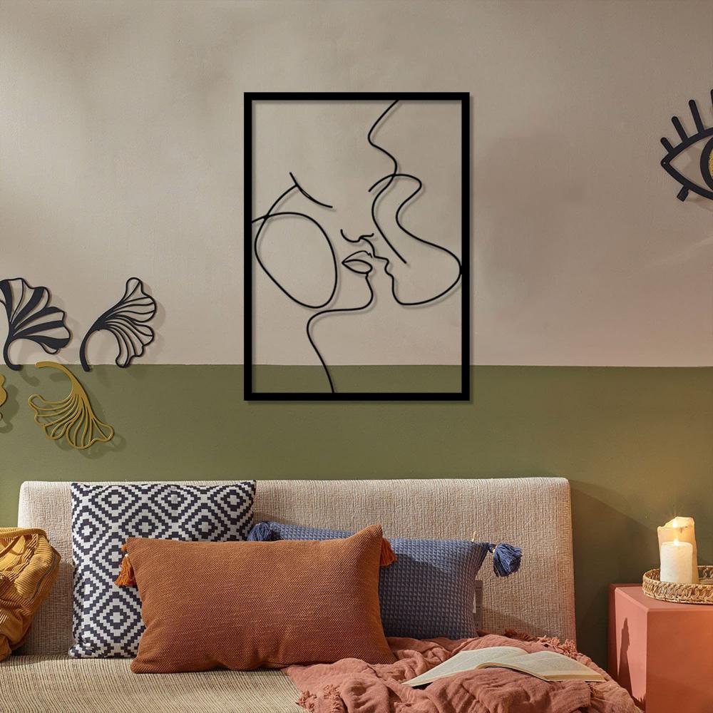 A modern bedroom setup with earthy tones, featuring a "Relationship Goals" metal wall art showing an abstract couple in minimalist lines, hung above a bed with green bedding.