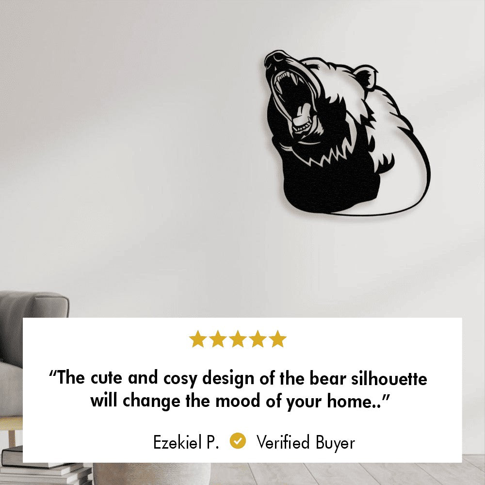 A black metal wall art piece of a roaring bear mounted on a plain white wall. Below the image is a five-star review from a verified buyer named Ezekiel P., stating: "The cute and cosy design of the bear silhouette will change the mood of your home."