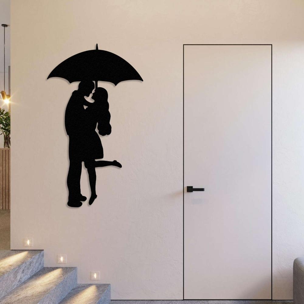 Black silhouette metal wall art of a couple under an umbrella, positioned near a minimalistic interior door and staircase with warm recessed lighting.