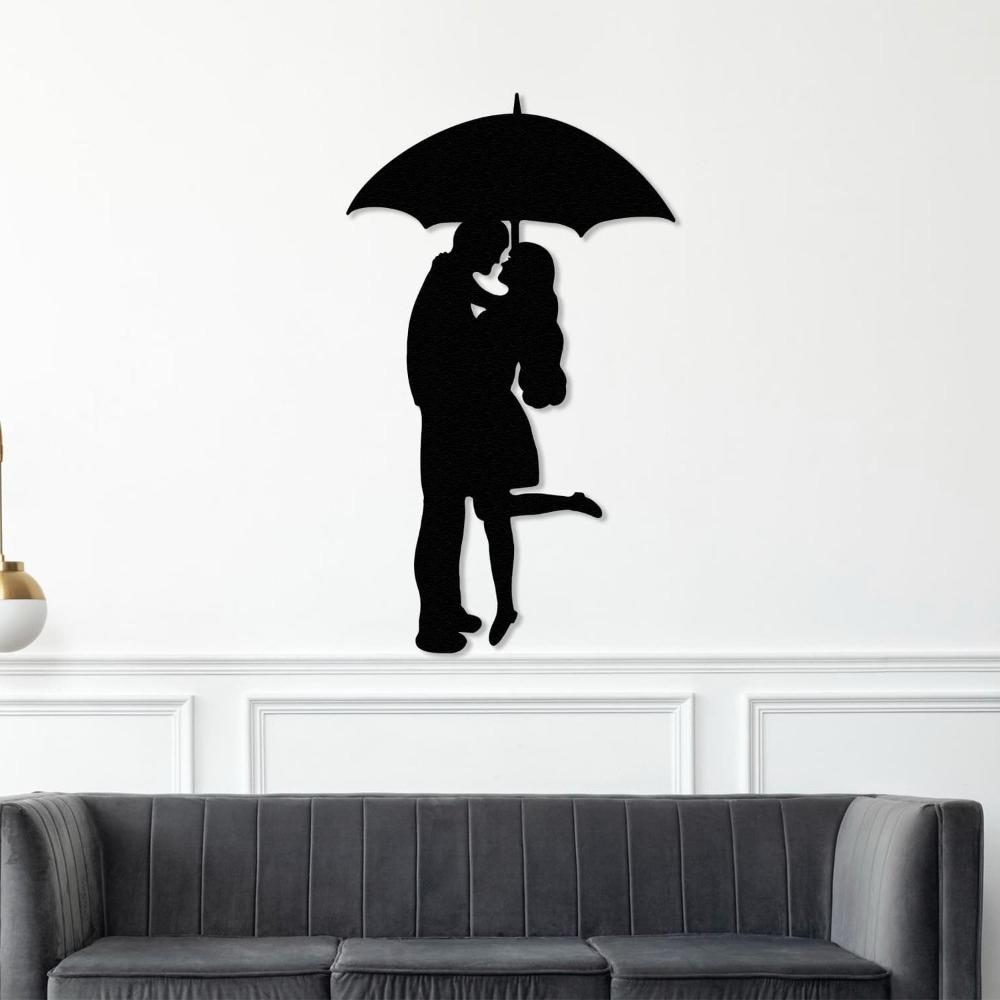 Black silhouette metal wall art of a romantic couple under an umbrella, mounted above a modern gray velvet couch in a classic white-paneled living room.