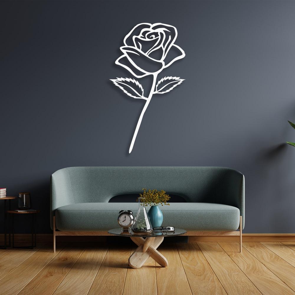 White rose-shaped metal wall art decor hanging on a dark blue wall above a modern teal sofa. A small wooden coffee table with a vase, books, and a clock completes the elegant room setting.