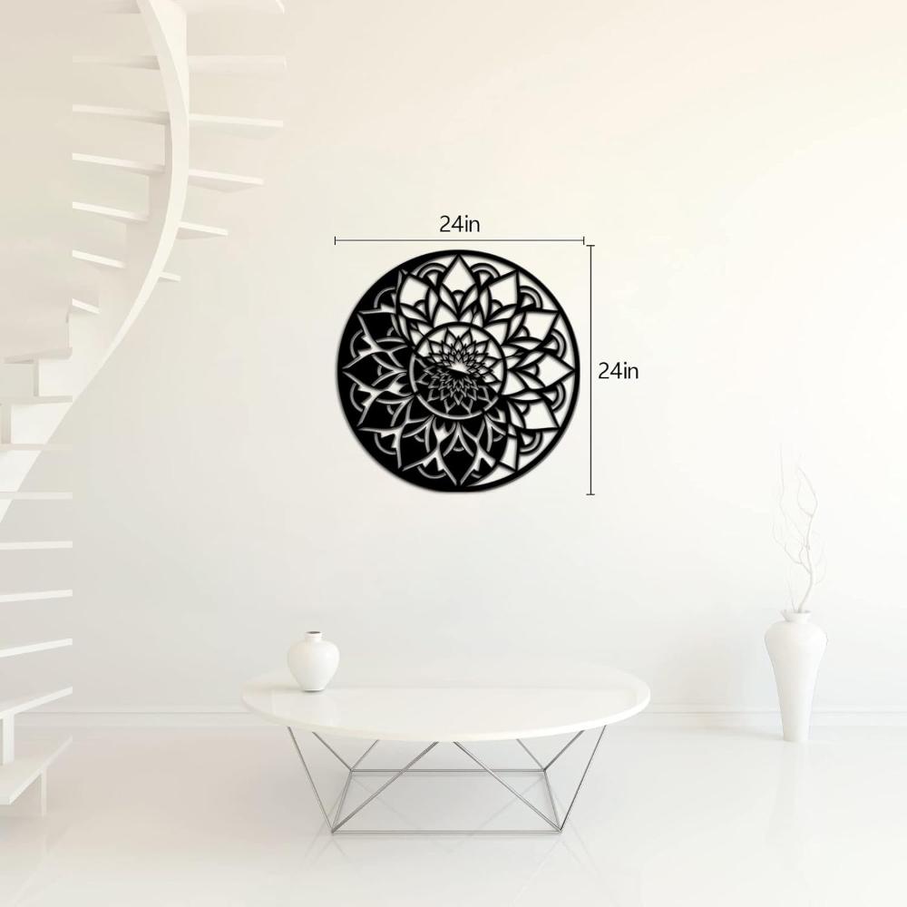 A round black metal wall art featuring a floral mandala design with a measurement of 24 inches, displayed in a bright, minimalistic living room with a modern white table and spiral staircase.