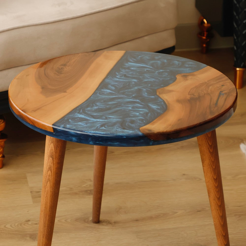 Close-up view of a round wooden table with blue resin accents, showcasing intricate patterns and natural wood grain design.