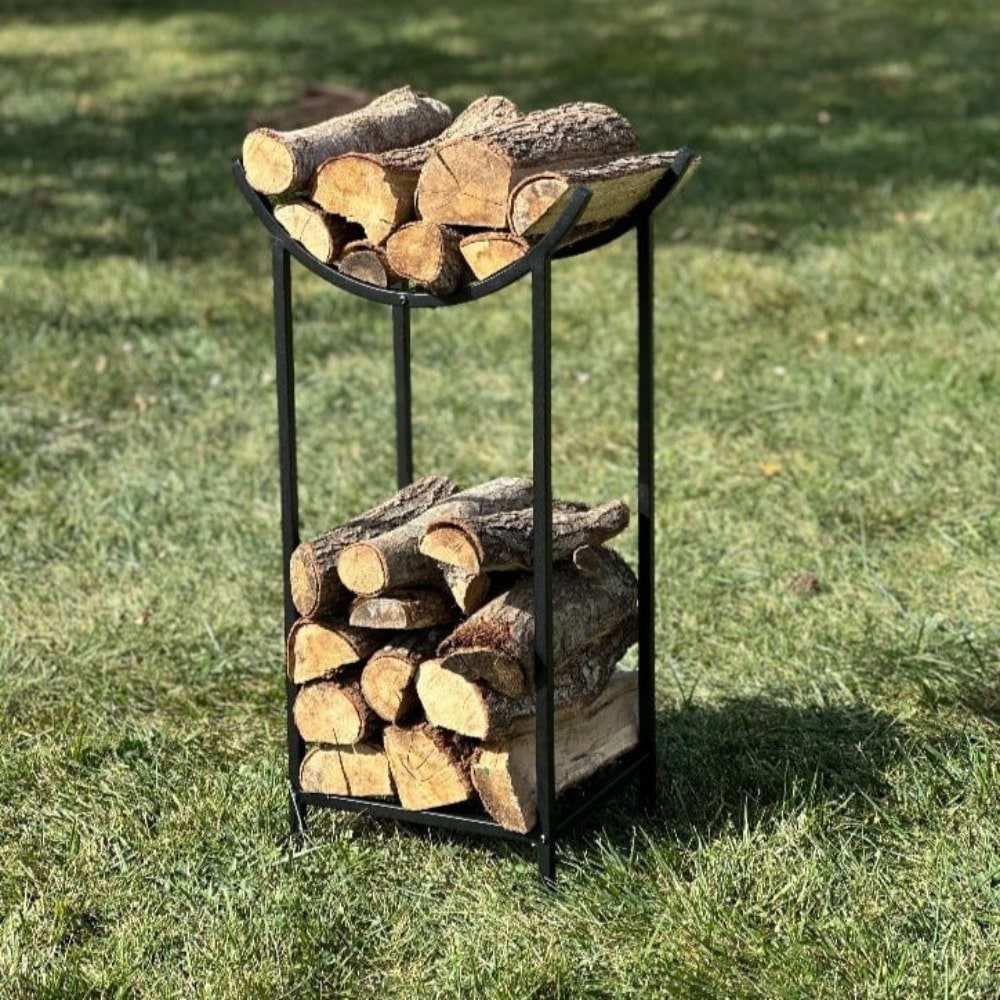 A minimalist black metal firewood holder with a practical dual-compartment design, holding neatly stacked logs and kindling, placed on a wooden board outdoors.