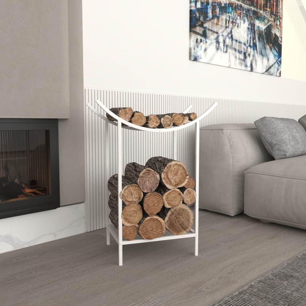 A modern white metal firewood holder with a dual-level design featuring a curved upper shelf for kindling and a lower compartment for logs, placed indoors near a fireplace