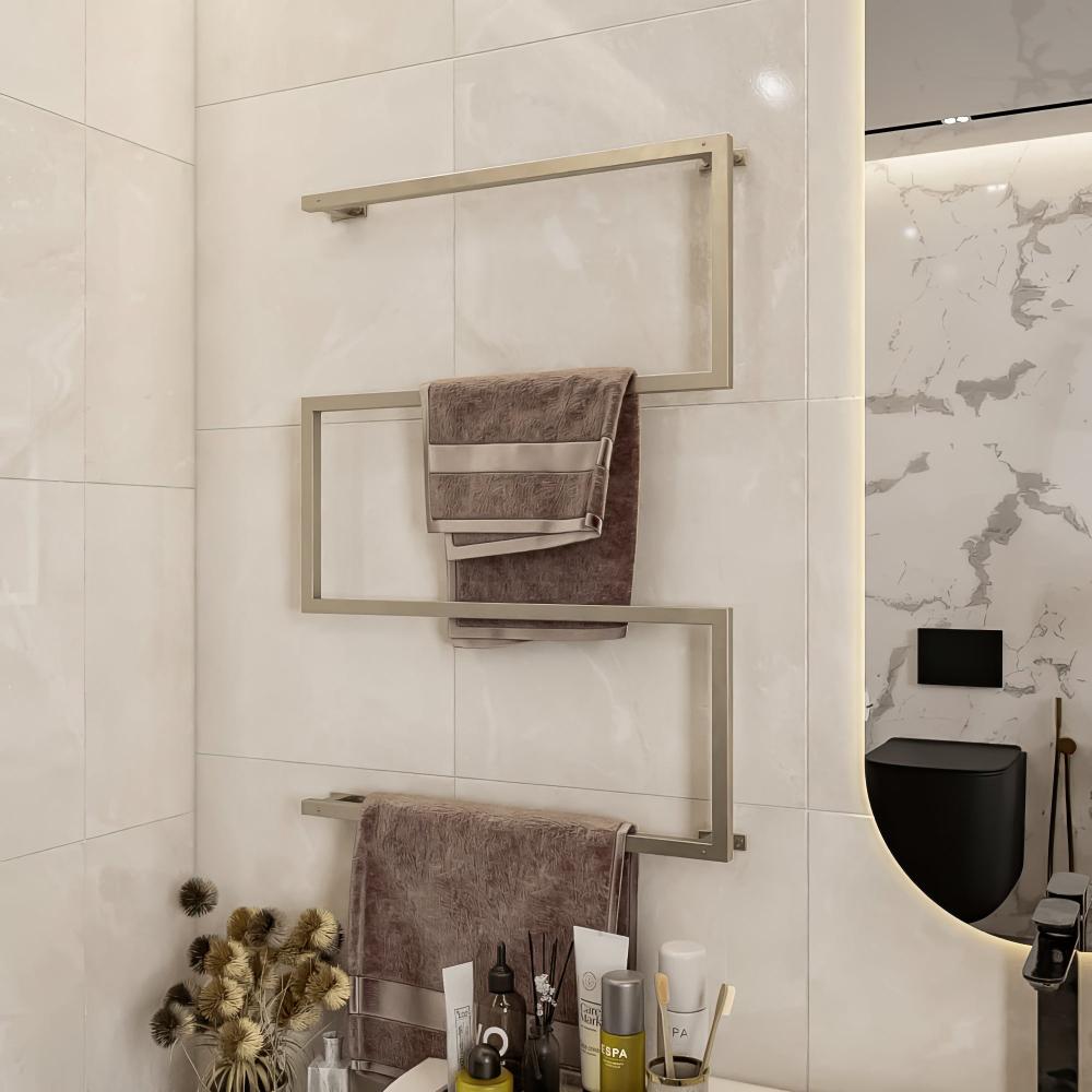 Wall-mounted towel holder in satin nickel finish, installed in a modern bathroom. The holder features a geometric design with multiple tiers for hanging towels. The backdrop includes a large bathtub, light-colored tiles, and a sleek toilet area, complementing the minimalist aesthetic.