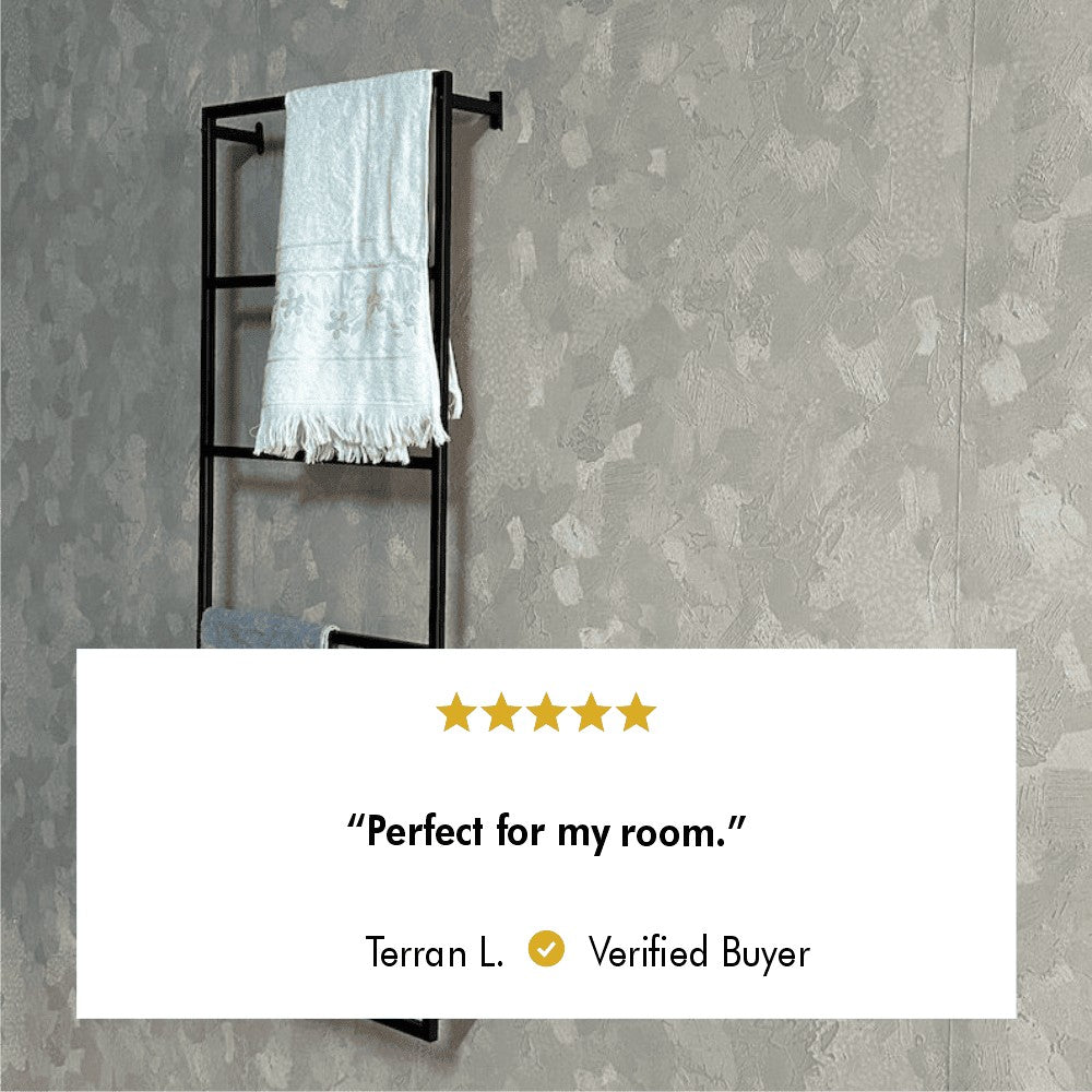 Wall-mounted black metal towel rack holding two towels, featured against a textured gray wall, accompanied by a five-star review stating, "Perfect for my room." from verified buyer Terran L.