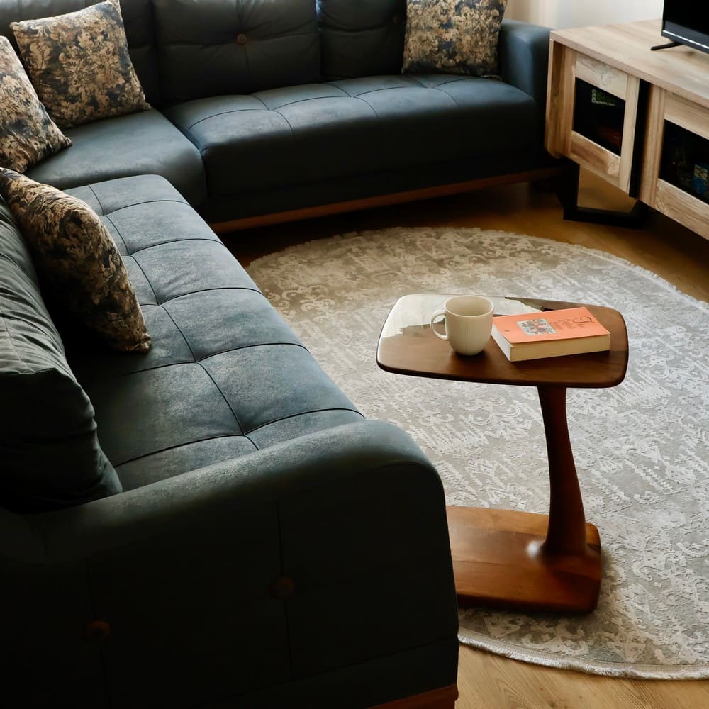 Walnut wood side table with a resin top, featuring a book and cup on its surface, situated in a cozy living room setting.