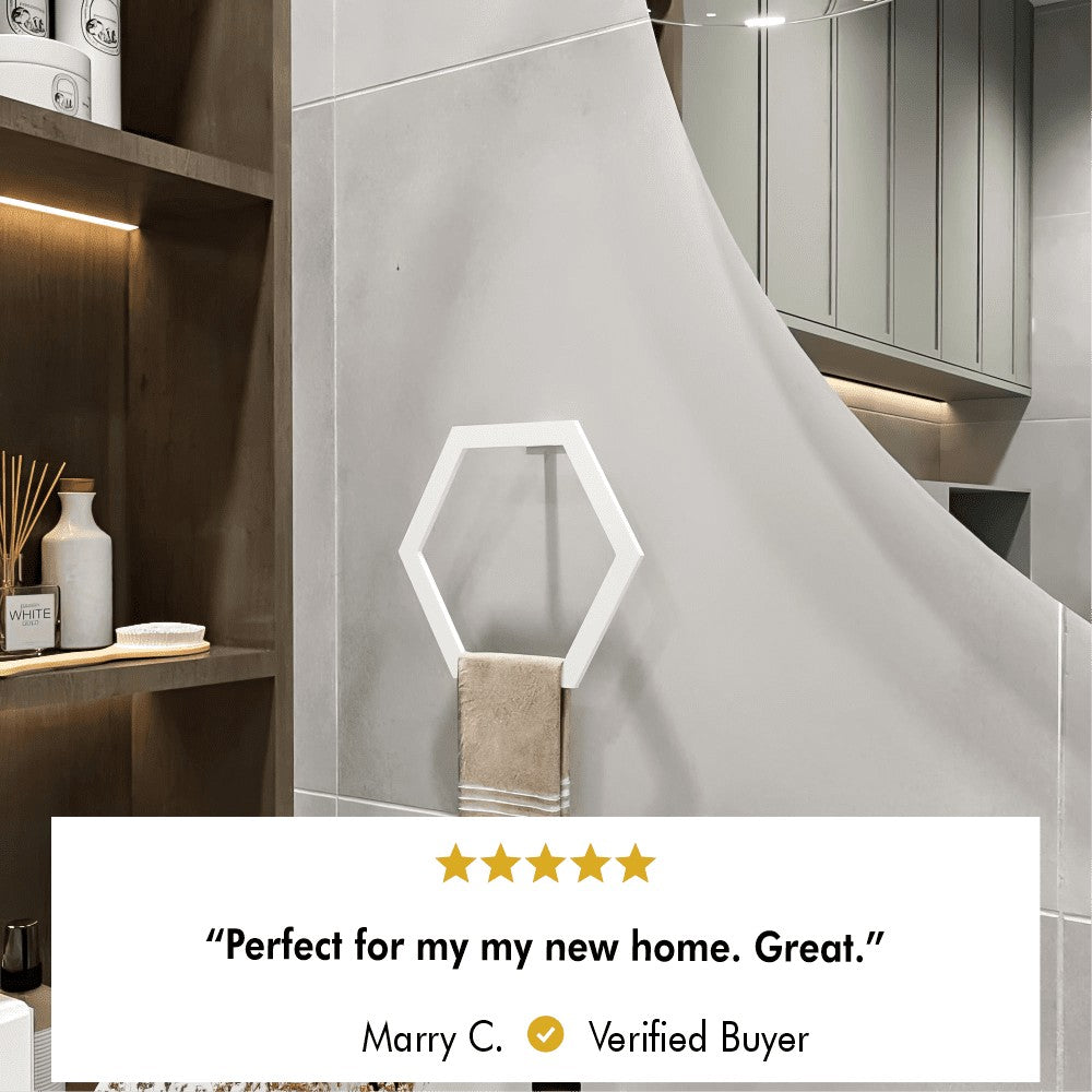 White hexagon-shaped towel ring mounted on a light gray bathroom wall, holding a beige towel, with a verified review stating, "Perfect for my new home. Great."