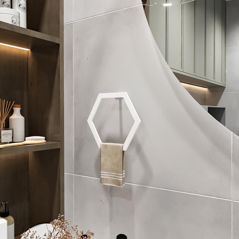 White hexagon towel ring displayed on a gray bathroom wall with a beige towel, next to wooden shelves with decorative items and modern lighting.