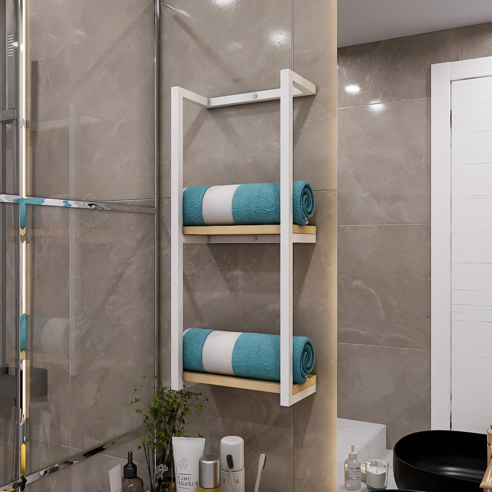 White metal bathroom shelf with a light wood base, holding neatly folded blue towels, installed on a beige tiled wall with bathroom accessories below