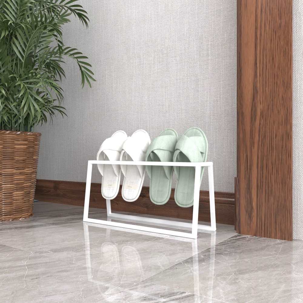 A white metal slipper holder showcasing a minimalist design, holding white and mint-green slippers, placed near a wooden trim and potted plant