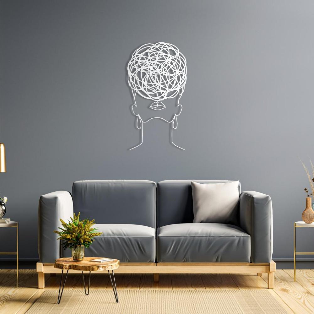 Elegant white metal wall art of a woman with intricate circular pattern hair, mounted on a blue wall above a contemporary gray sofa.