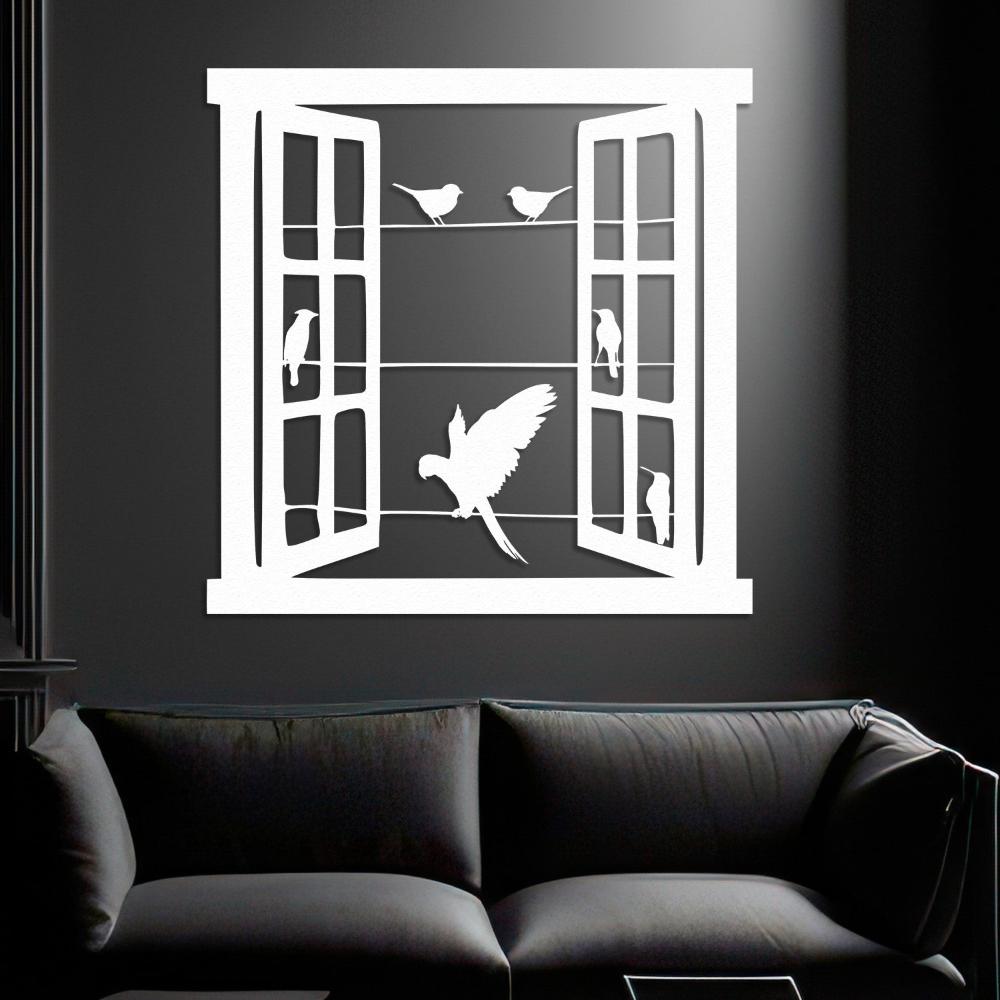 White metal wall art depicting an open window with bird silhouettes perched on wires, placed on a dark wall above a modern black sofa, creating a striking contrast.