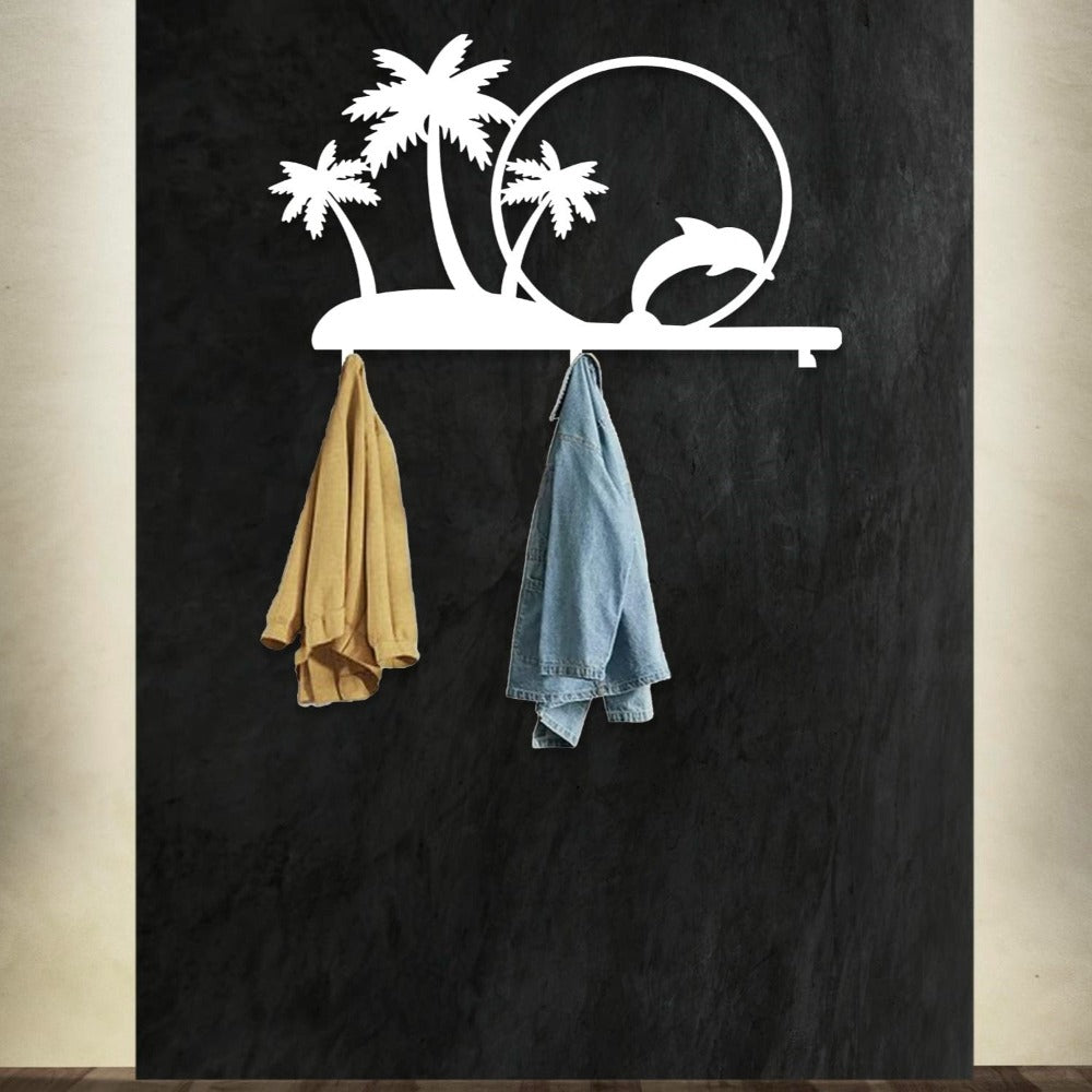 A white metal wall-mounted rack featuring palm trees and a dolphin jumping through a circle, offering a tropical-themed design. The rack holds a beige jacket and a denim jacket, set against a dark wall, providing a stylish and functional decor piece.