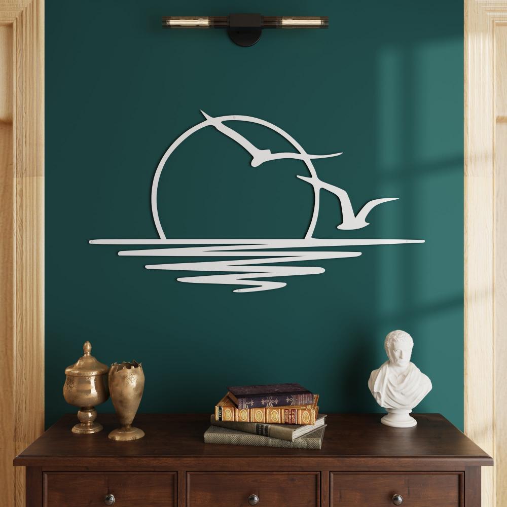 White metal wall art of a sunrise with birds on a green wall, above a wooden sideboard with decorative items.