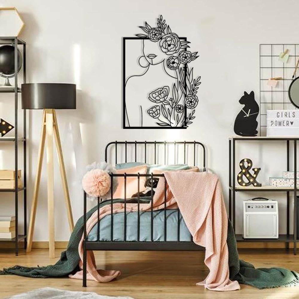 A stylish metal wall decor featuring a minimalist woman silhouette with floral designs, displayed in a modern girl's bedroom with a cozy bed, lamp, and playful decor elements.