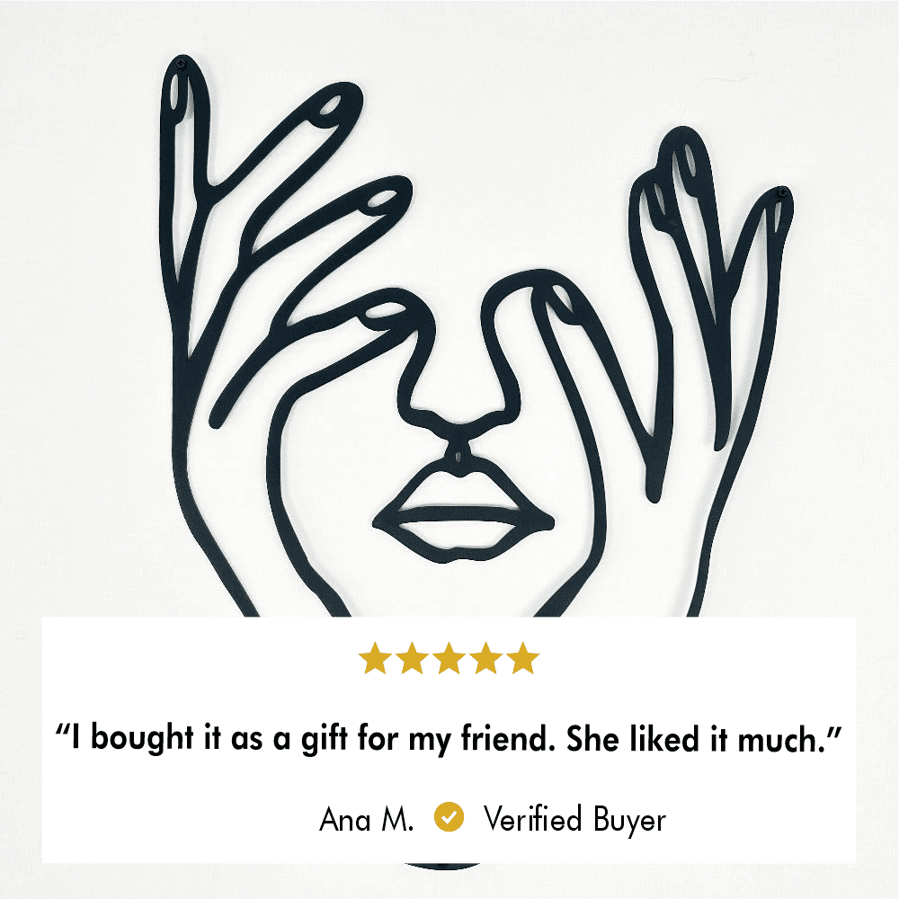  Minimalist metal wall art of a woman's face with hands framing it on a white background. A verified buyer review below states, "I bought it as a gift for my friend. She liked it much," rated 5 stars by Ana M.