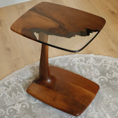 Close-up of a uniquely designed wooden side table with a resin-coated top featuring elegant wood grain patterns, placed on a decorative rug.